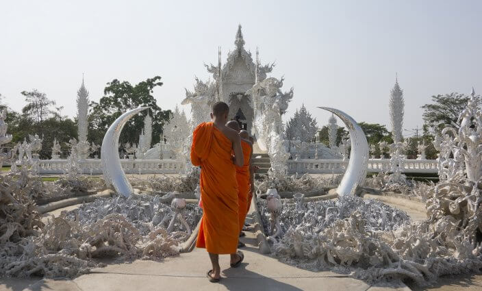 Mönch vor Wat Rong Khun Tempel in Thailand